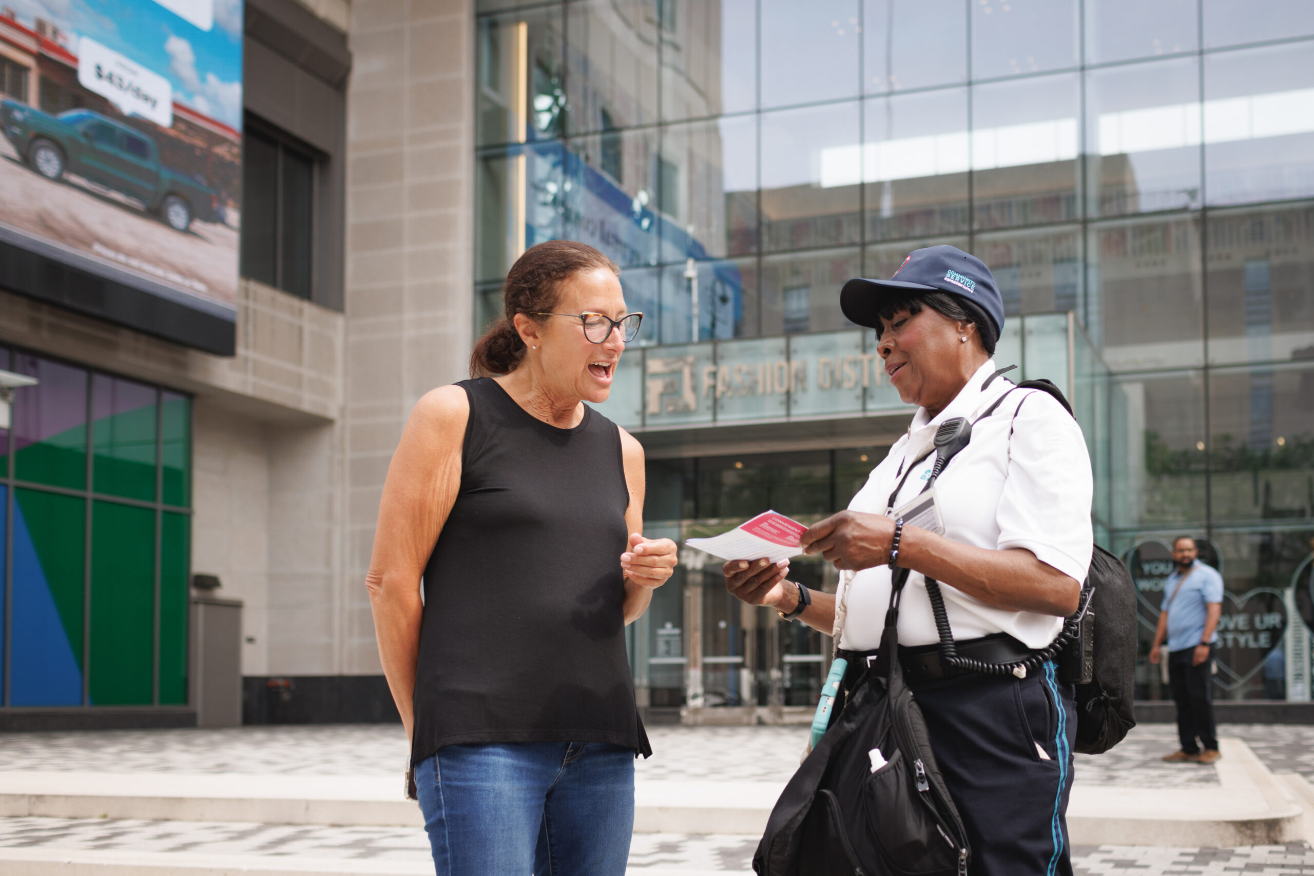 A CCD community service representative (CSR for short) safety ambassador wearing a uniform and carrying a 2-way radio, giving a person directions.