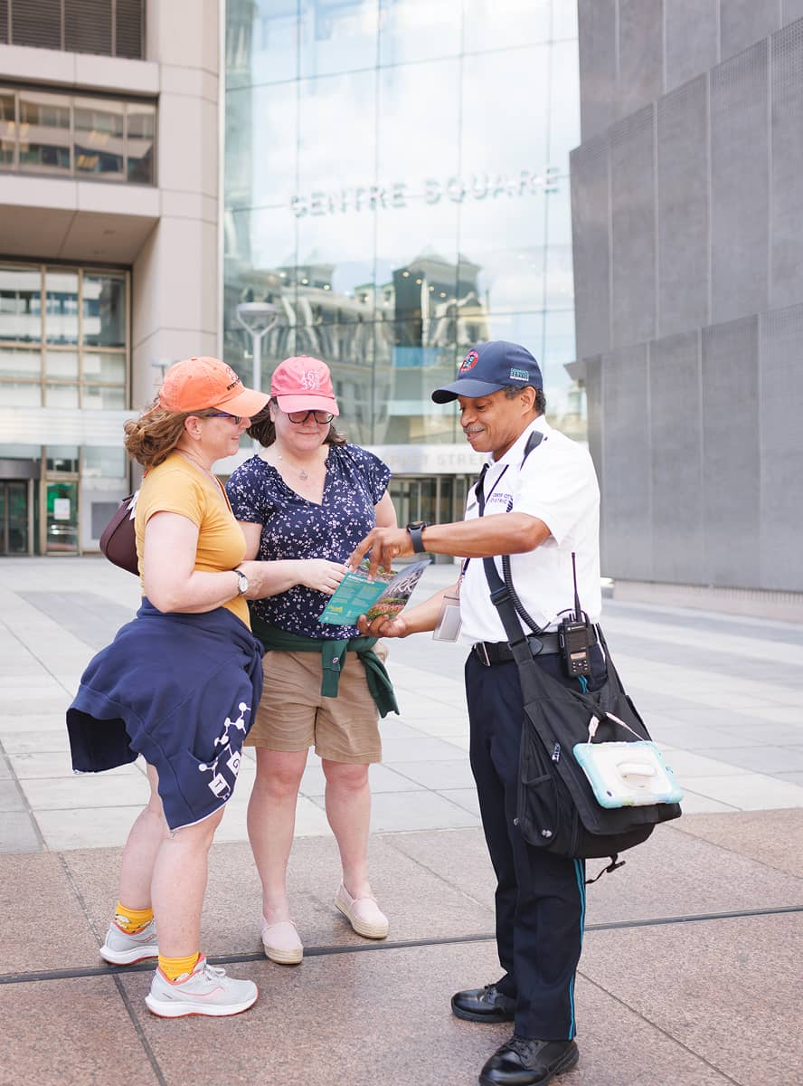 CCD community service representative (CSR for short) safety ambassador wearing a uniform and carrying a 2-way radio, giving people directions.