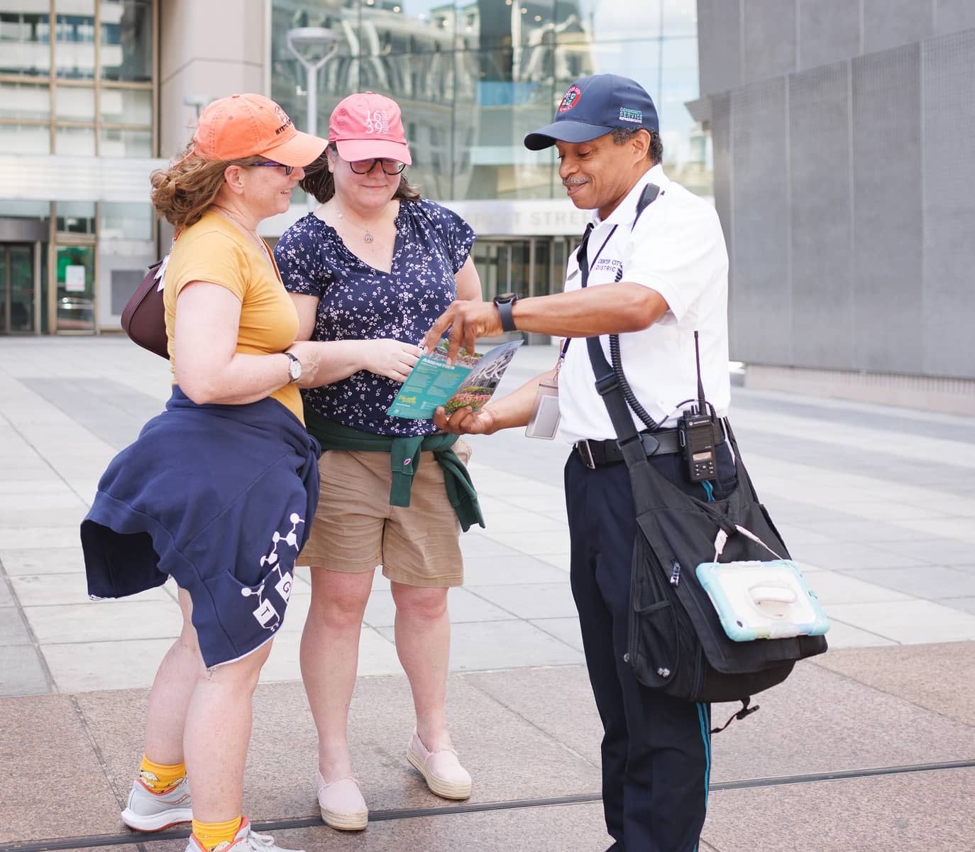 CCD community service representative (CSR for short) safety ambassador wearing a uniform and carrying a 2-way radio, giving people directions.