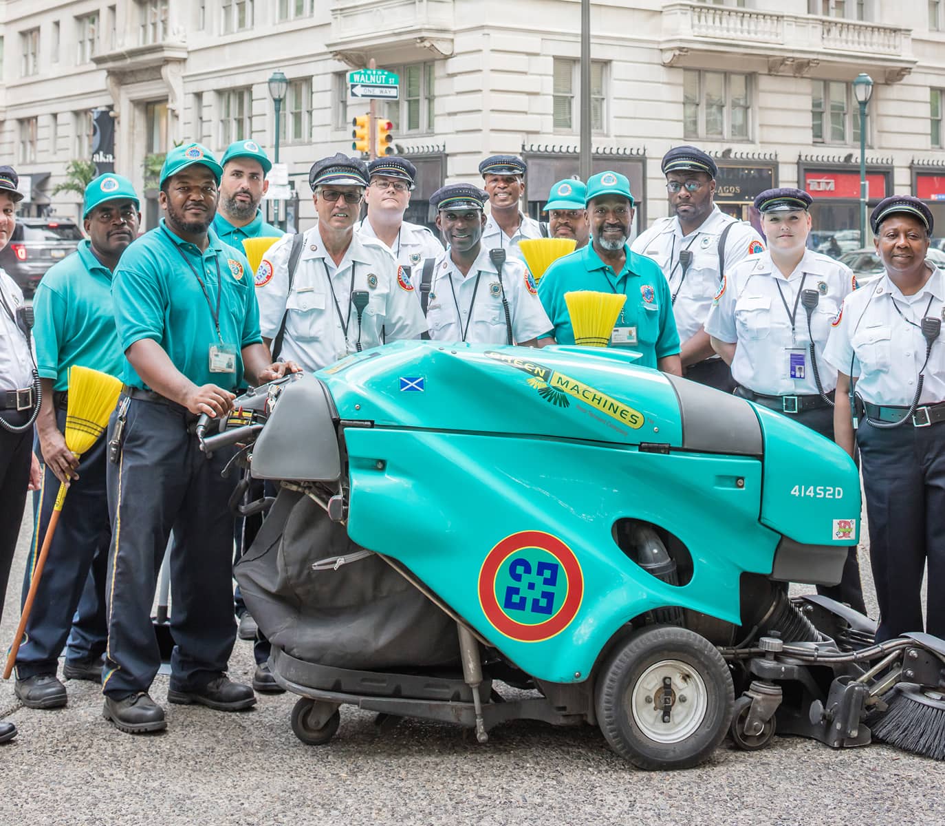 Center City District staff group photo which includes Community Service Representatives, sidewalk cleaning maintenance staff, and a green machine.