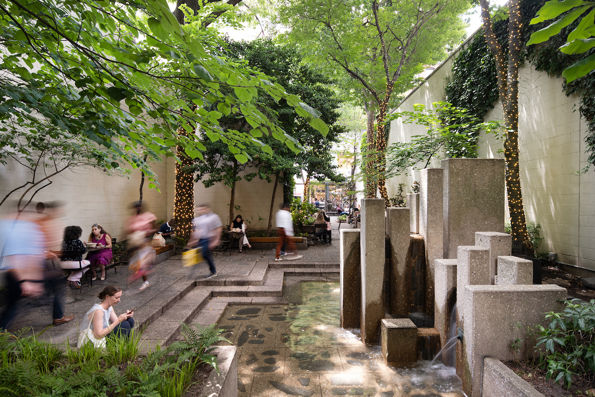 Fountain at John F Collins Park with people sitting and walking through the park