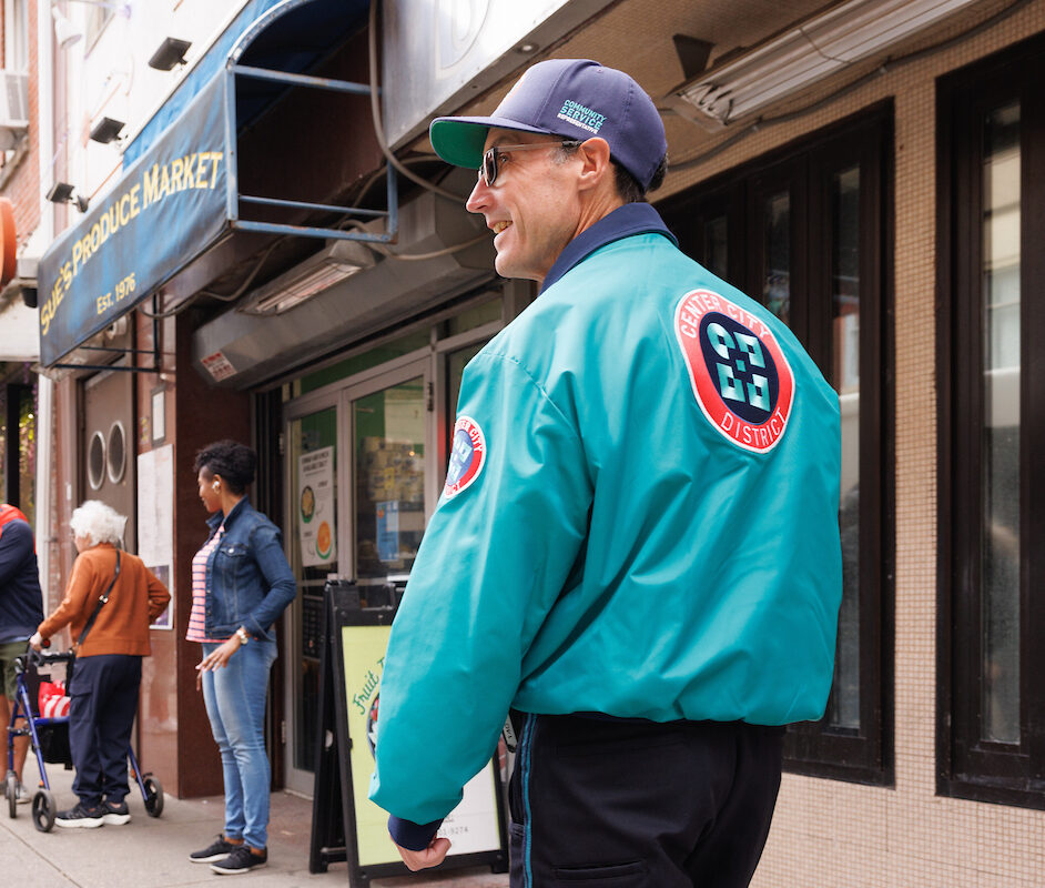 CCD community service representative (CSR for short) safety ambassador wearing a teal jacket, baseball cap and 2-way radio, on patrol.