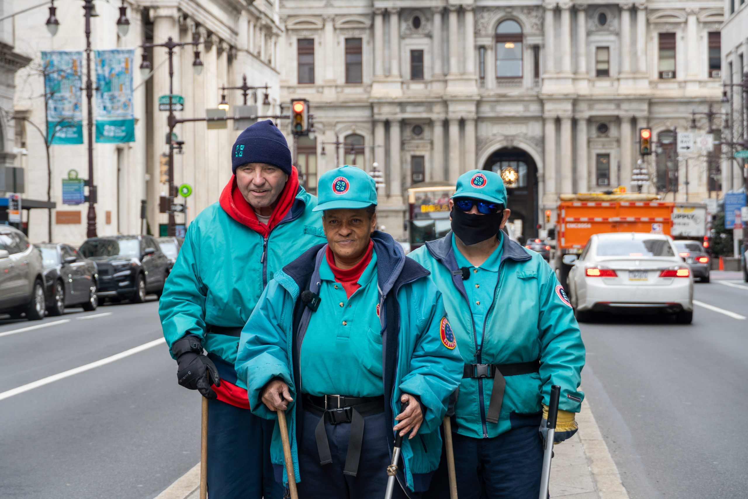 Three long-term CCD sidewalk sweepers posing in front of Philadelphia's City Hall.