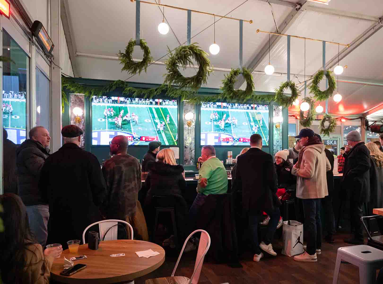 Winter at Dilworth Park inside the Rothman Orthopaedic Cabin people eating, drinking and watching a football game.